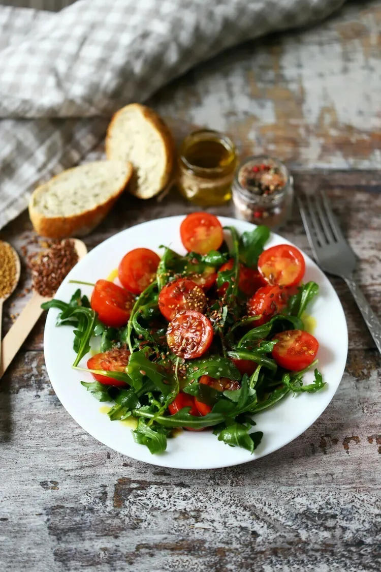 Fresh arugula salad with tomato, vinegar and olive oil