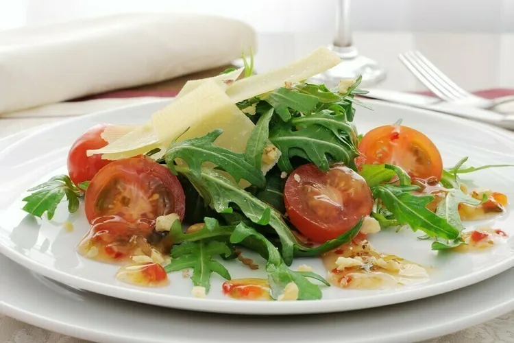 Arugula salad with tomatoes, pine nuts and parmesan cheese