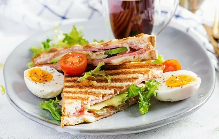 Bacon, egg and tomato club sandwiches with chives and parsley