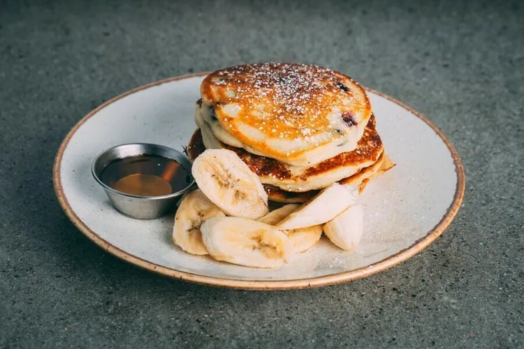 Chocolate banana protein pancakes with candies and maple syrup