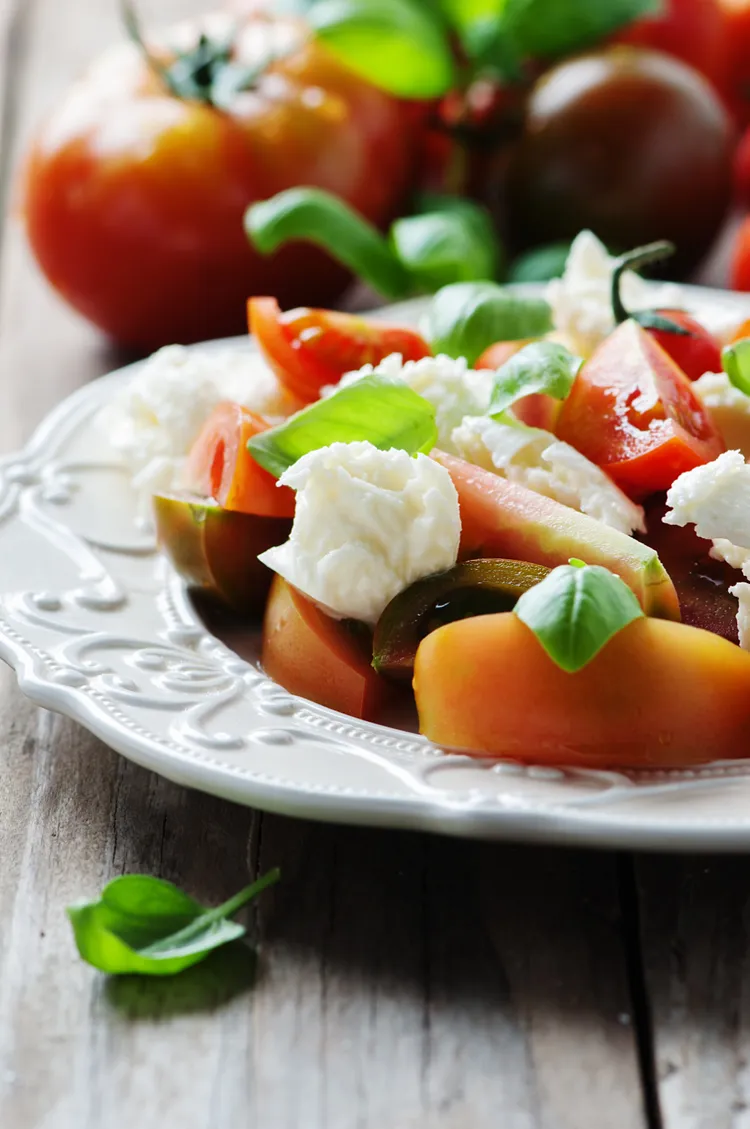 Summery tomato, peach and goat cheese salad with garlic, pistachios and baguette