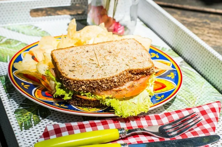 Whole wheat hummus sandwich with tomato, pickles and lettuce